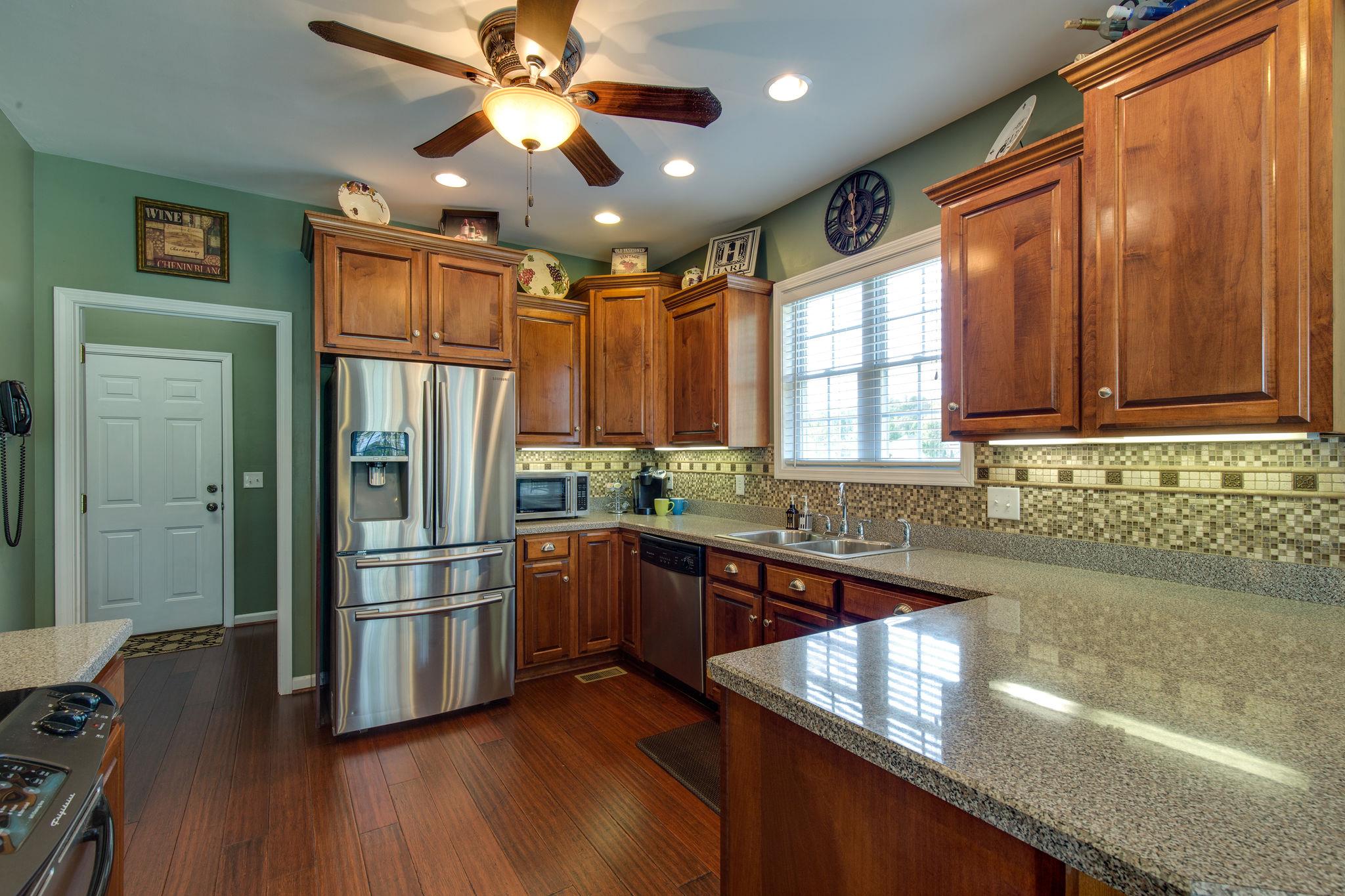 1207 Maple Hill Road Lebanon, TN 37087 - Photo 9 of 29 a kitchen with stainless steel appliances granite countertop a refrigerator a sink dishwasher a stove and white countertops with wooden floor