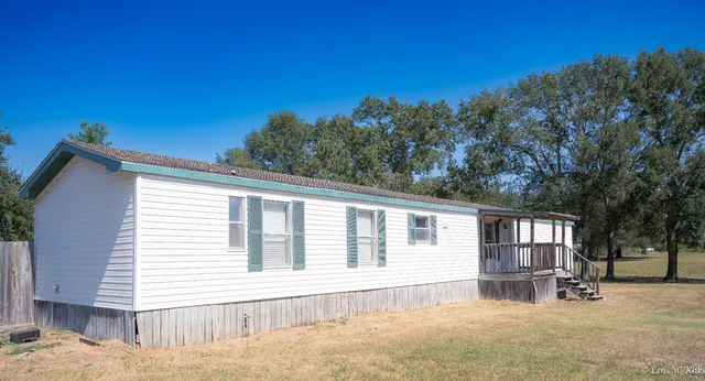 a backyard of a house with wooden fence and large trees