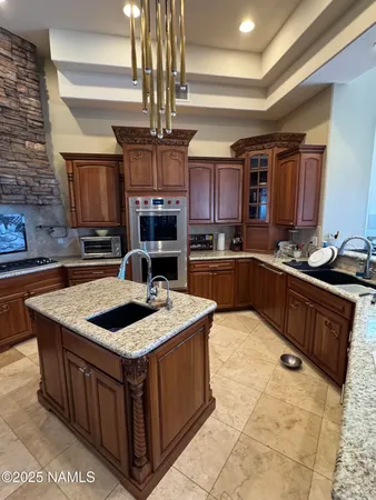 a kitchen with stainless steel appliances granite countertop a sink a stove a counter space and cabinets