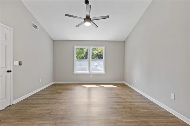 an empty room with wooden floor and a ceiling fan