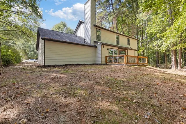 a backyard of a house with large trees and wooden fence