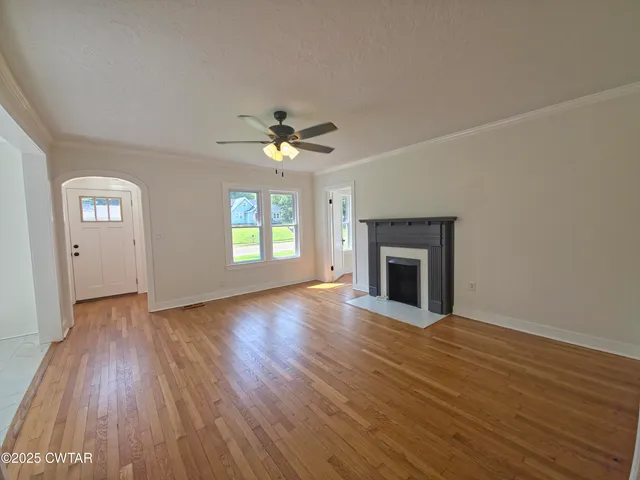a view of an empty room with a fireplace and a window