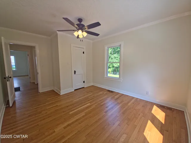 a view of empty room with wooden floor and fan