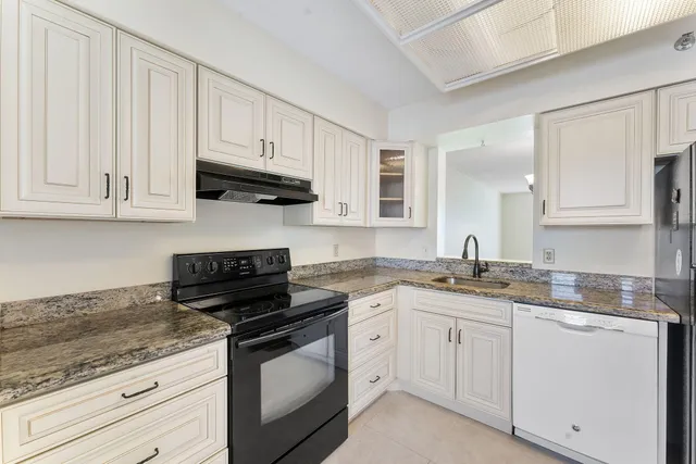 a kitchen with granite countertop white cabinets and a stove