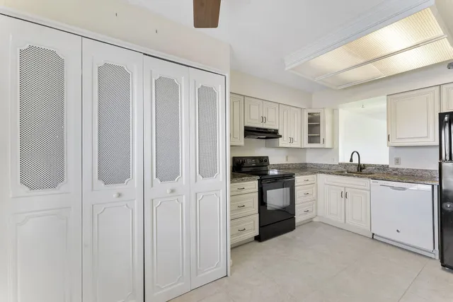 a large white kitchen with granite countertop stainless steel appliances and white cabinets