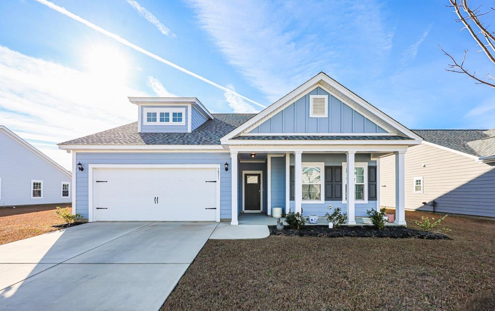 View of front of property with a porch, a shingled roof, concrete driveway, an attached garage, and board and batten siding