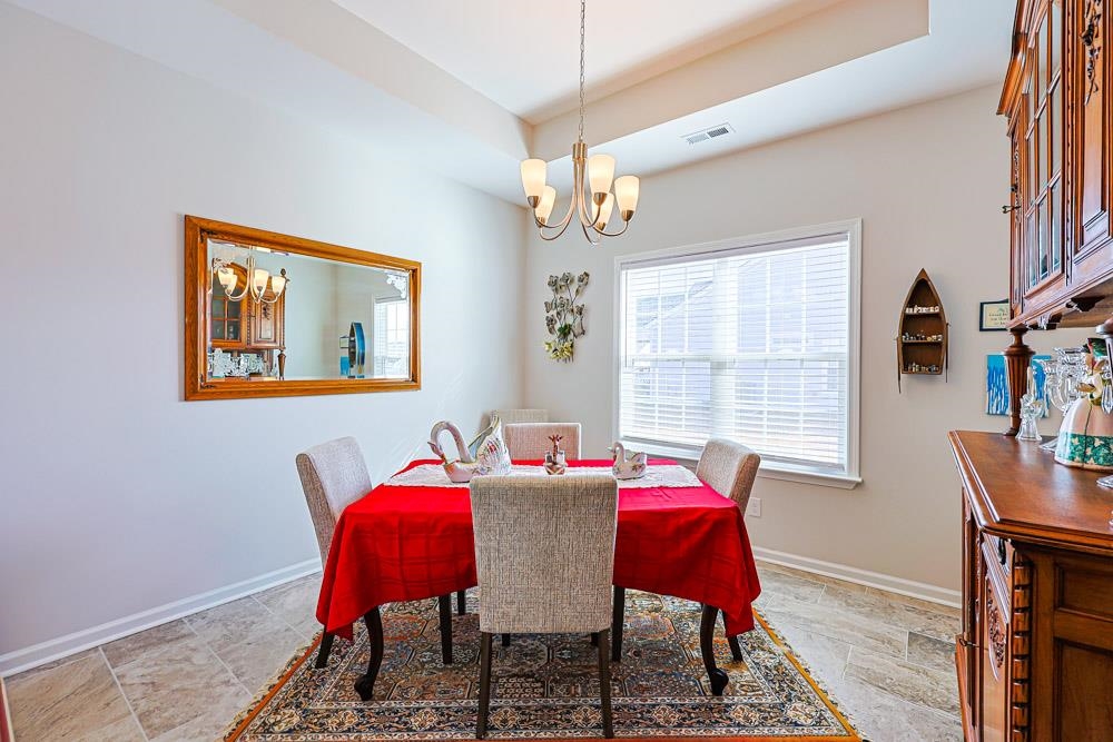 2821 Rivolet Drive Conway, SC 29526 - Photo 25 of 34 Dining room with a tray ceiling, stone finish flooring, and a chandelier