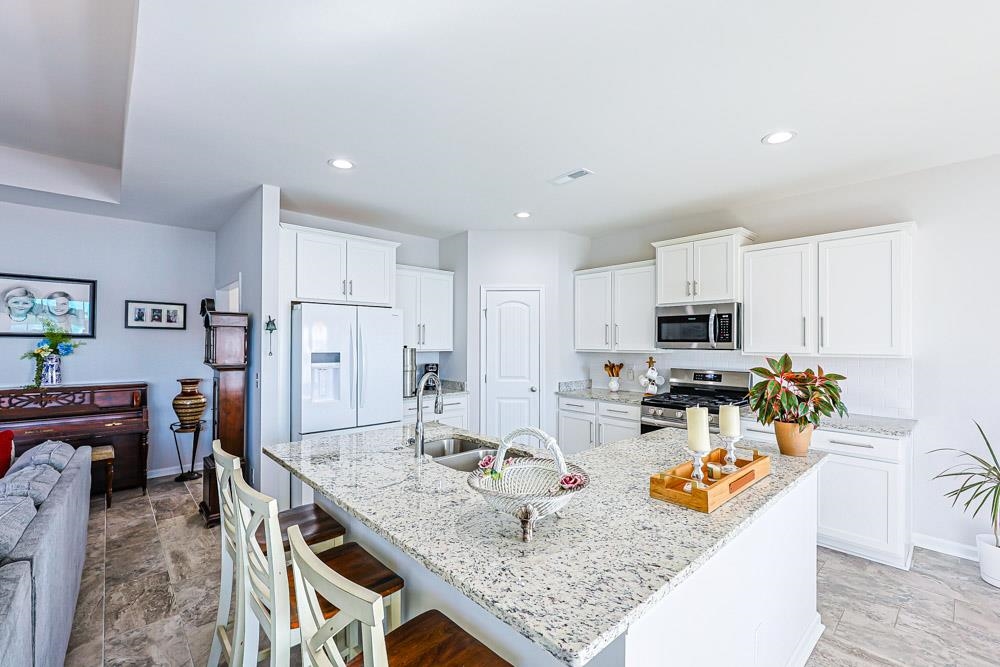 2821 Rivolet Drive Conway, SC 29526 - Photo 5 of 34 Kitchen with white cabinetry, stainless steel appliances, light stone countertops, a kitchen bar, and recessed lighting