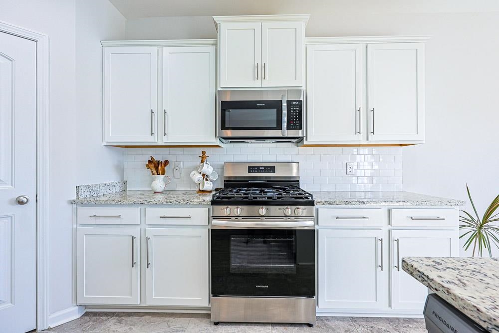 2821 Rivolet Drive Conway, SC 29526 - Photo 6 of 34 Kitchen with stainless steel appliances, white cabinetry, light stone countertops, and decorative backsplash
