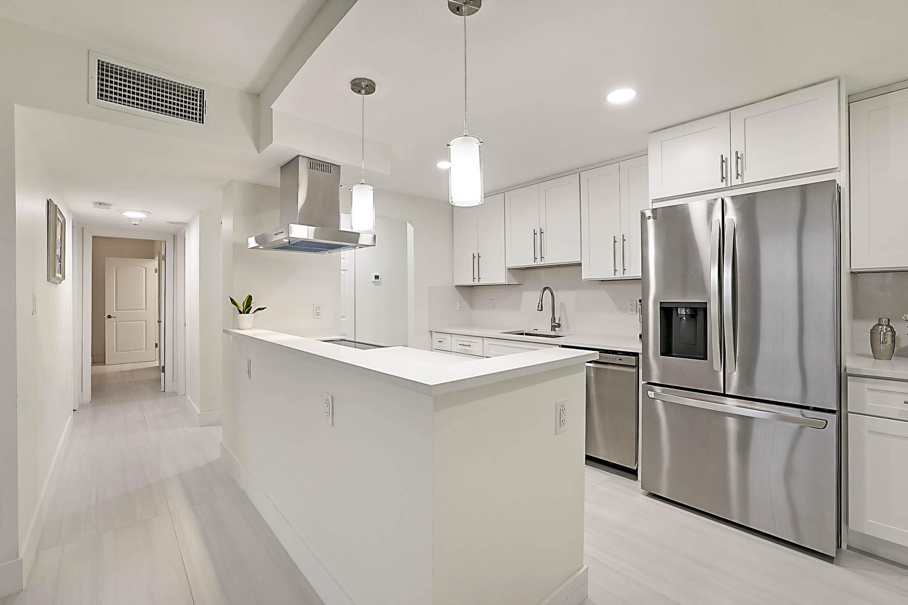 2121 North Ocean Boulevard, Unit 806W Boca Raton, FL 33431 - Photo 13 of 63 a kitchen with kitchen island white cabinets and stainless steel appliances