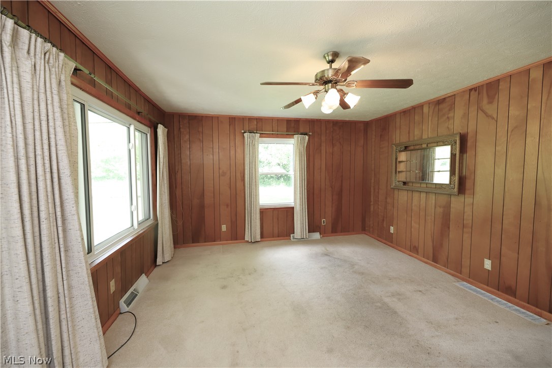 Carpeted empty room with wooden walls and ceiling fan
