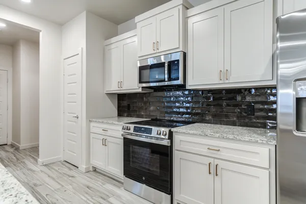 a kitchen with stainless steel appliances granite countertop a stove a microwave and a white cabinets