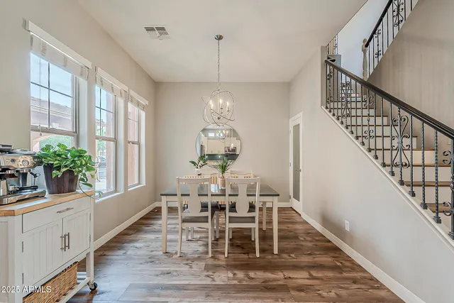 a dining room with wooden floor a chandelier a wooden table and chairs