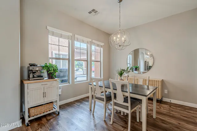 a dining room with wooden floor a chandelier a wooden table and chairs