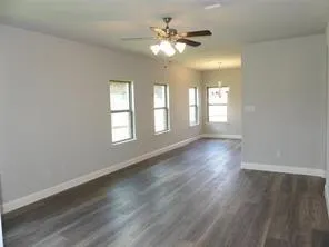 a view of an empty room with window and wooden floor