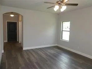 an empty room with wooden floor closet and windows