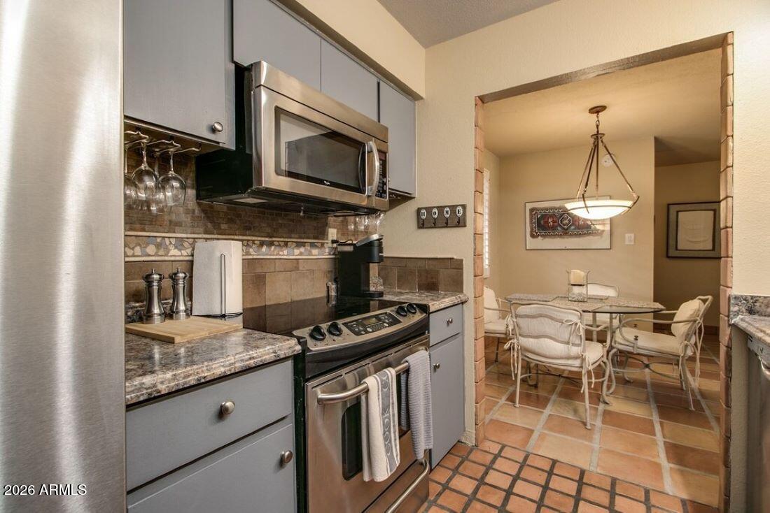 7625 East Camelback Road, Unit B117 Scottsdale, AZ 85251 - Photo 12 of 27 a kitchen with stainless steel appliances granite countertop a stove a sink and a microwave