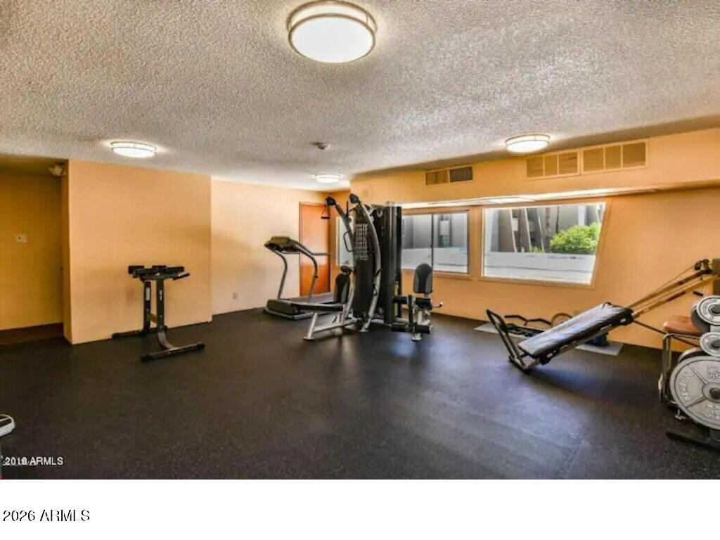 7625 East Camelback Road, Unit B117 Scottsdale, AZ 85251 - Photo 23 of 27 a living room with gym equipment and a large window