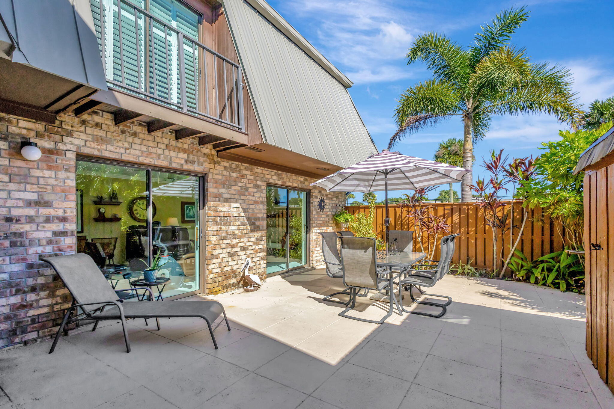 1420 Ocean Way, Unit 23B Jupiter, FL 33477 - Photo 5 of 37 a view of a patio with table and chairs under an umbrella with a barbeque