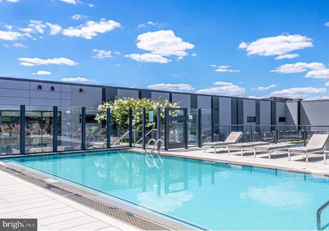 a room with stainless steel appliances kitchen island granite countertop a table chairs and a wooden floor