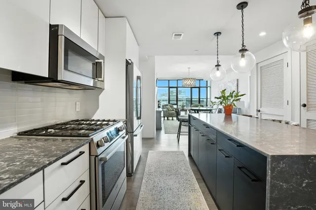 a kitchen with stainless steel appliances granite countertop a sink a stove and a wooden floors