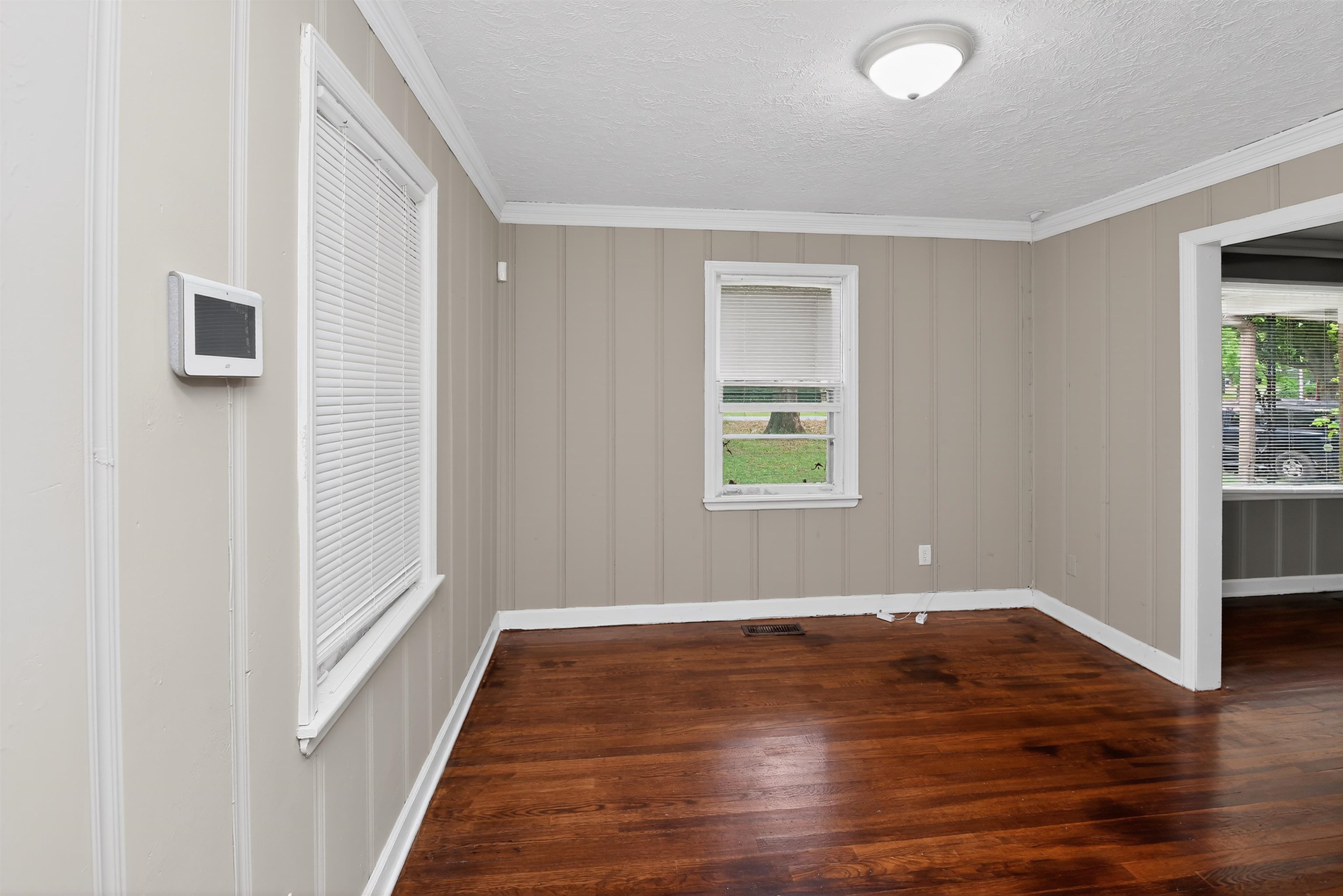 2840 Allen Road Memphis, TN 38128 - Photo 20 of 31 Room featuring wood-finish flooring, vertical paneling walls, baseboards, crown molding, and a flush-mount ceiling light fixture