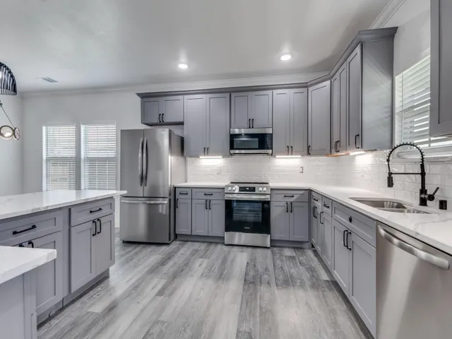 a kitchen with stainless steel appliances granite countertop a refrigerator a stove top oven a sink dishwasher and wooden cabinets with wooden floor