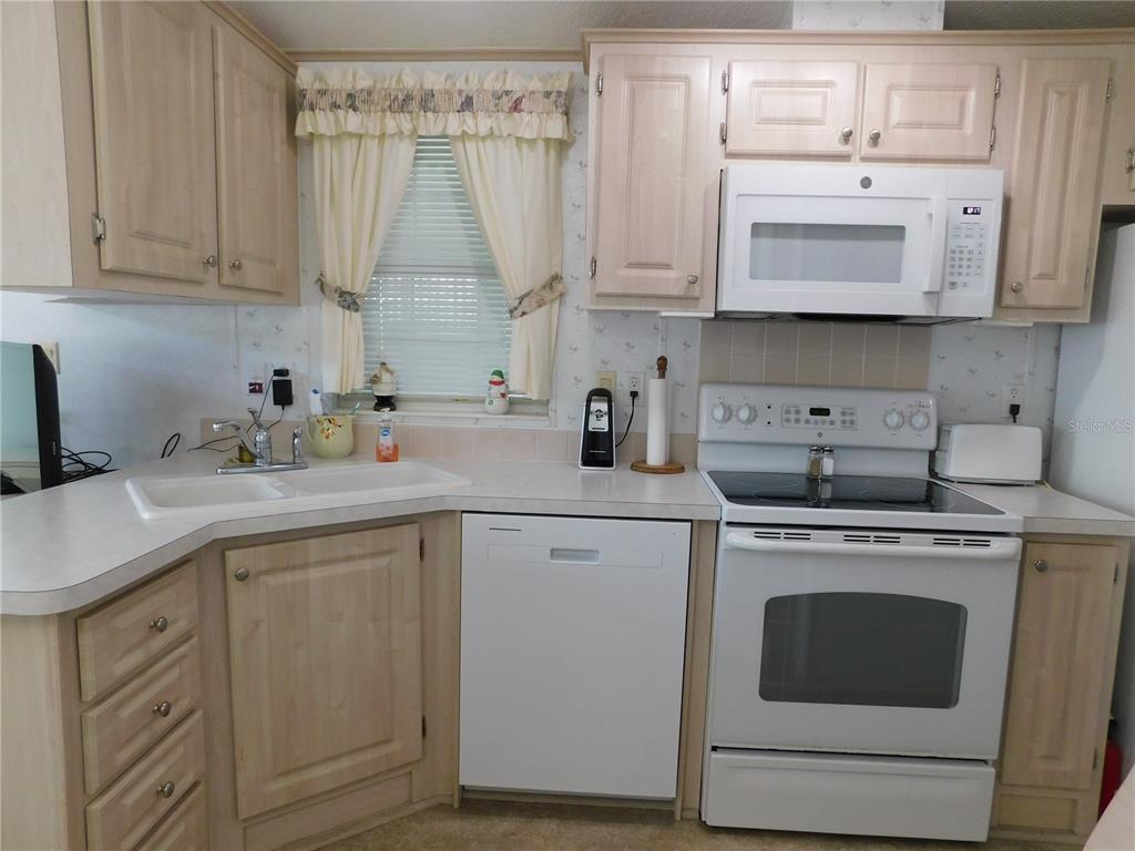 1385 Pine Island Drive St. Cloud, FL 34771 - Photo 8 of 28 a kitchen with stainless steel appliances granite countertop white cabinets a sink and dishwasher
