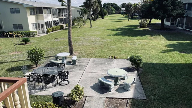 a view of a patio with table and chairs potted plants and large tree
