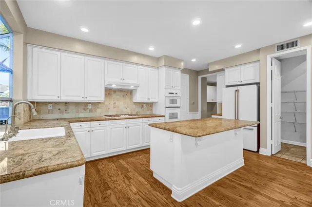 a large kitchen with stainless steel appliances granite countertop a large counter top a sink and a refrigerator