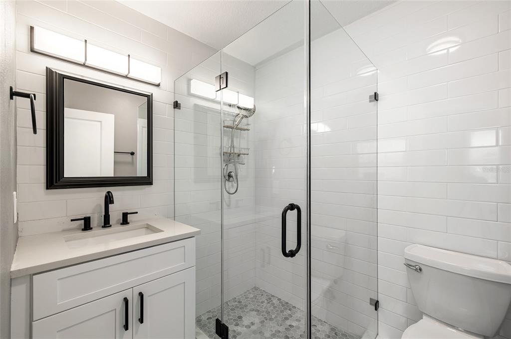 231 East Madeira Avenue Madeira Beach, FL 33708 - Photo 26 of 60 a bathroom with a granite countertop sink a mirror and shower