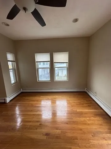 a view of an empty room with window and wooden floor