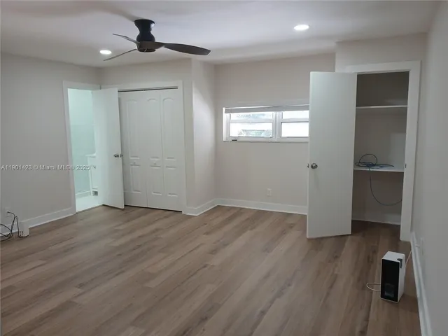 an empty room with wooden floor closet and windows