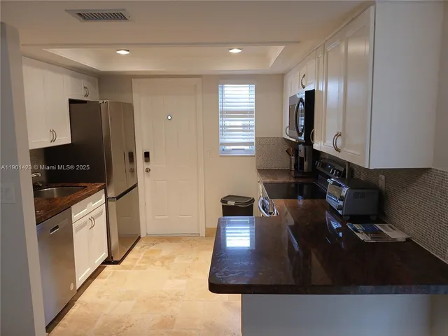 a kitchen with stainless steel appliances granite countertop a sink a stove and a refrigerator