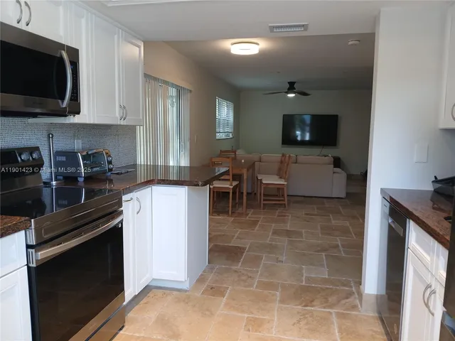 a kitchen with stainless steel appliances granite countertop a stove top oven a sink a dining table and chairs