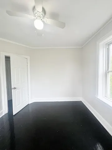 an empty room with a window and a ceiling fan