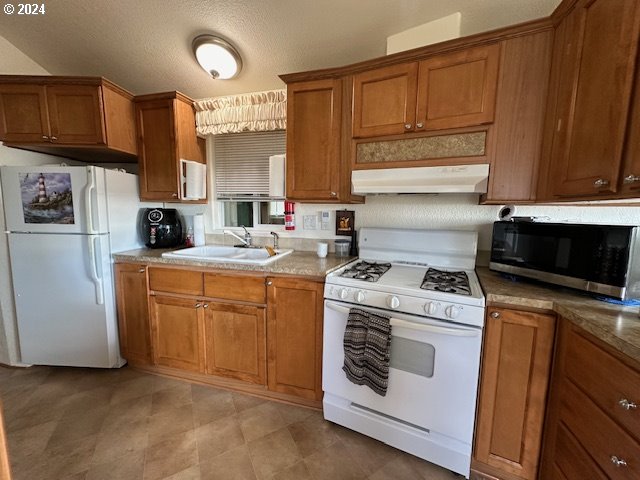 15061 Highway 101, Unit 4 Brookings, OR 97415 - Photo 6 of 12 a kitchen with a stove top oven sink and cabinets
