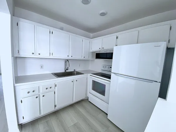 a kitchen with white cabinets sink and white appliances