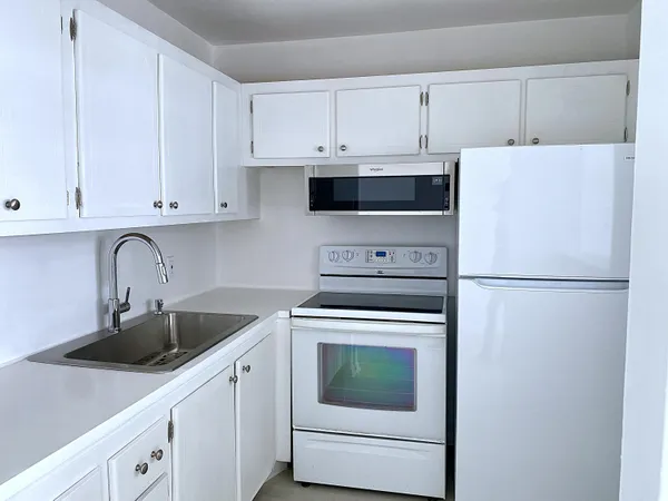 a kitchen with white cabinets and white appliances