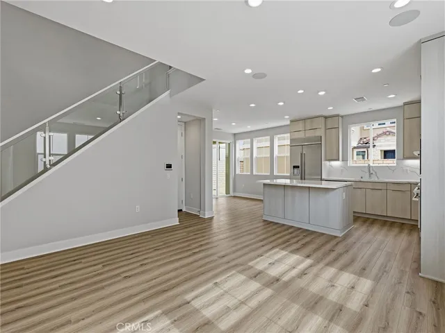 a kitchen with stainless steel appliances granite countertop a sink a stove a refrigerator and white cabinets with wooden floor