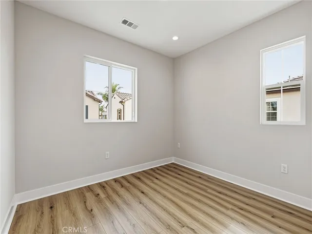 a view of an empty room with wooden floor and closet