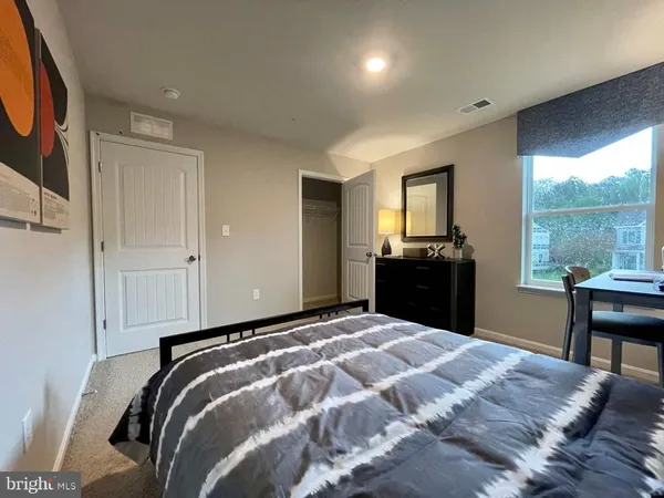 a bedroom with a bed and a dresser next to a window