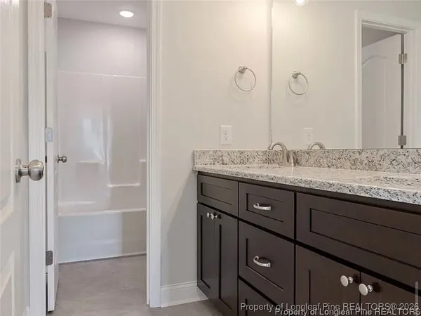 a bathroom with a granite countertop sink two mirror and shower