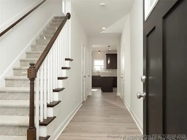 a view of a hallway with wooden floor and staircase