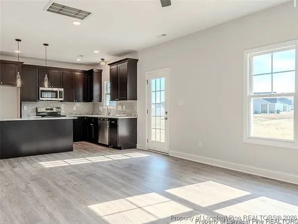 a large kitchen with kitchen island a large counter top space a sink stainless steel appliances and cabinets