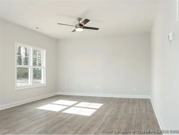 an empty room with a window and ceiling fan