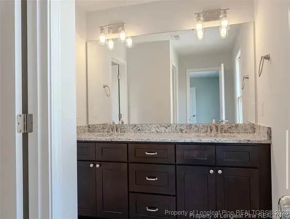a bathroom with a granite countertop sink a mirror and a shower