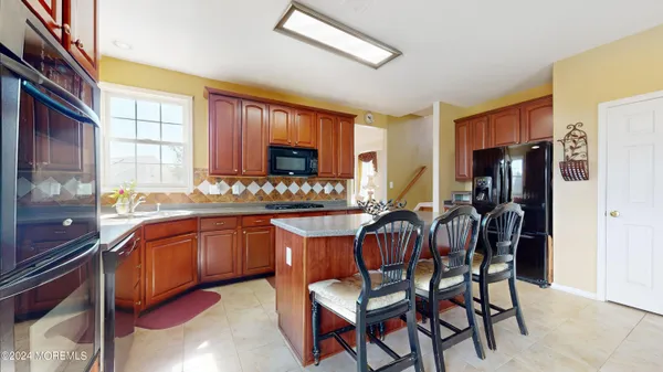 a kitchen with stainless steel appliances granite countertop wooden cabinets a dining table and chairs