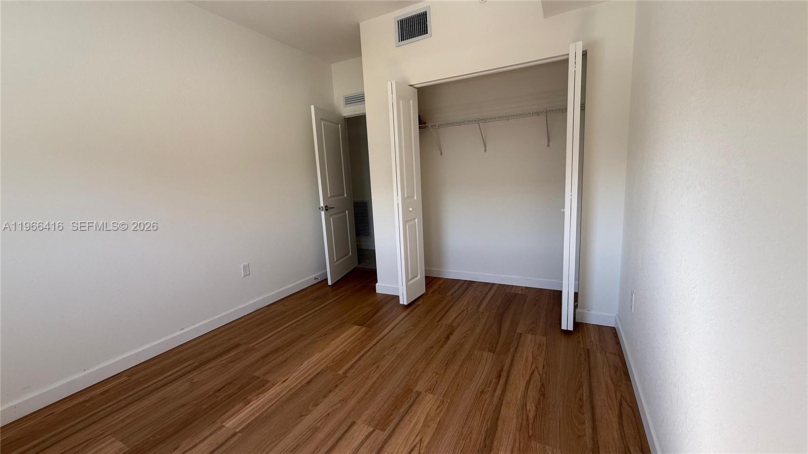 12420 Southwest 248th Street, Unit 10 Homestead, FL 33032 - Photo 15 of 16 an empty room with wooden floor and closet