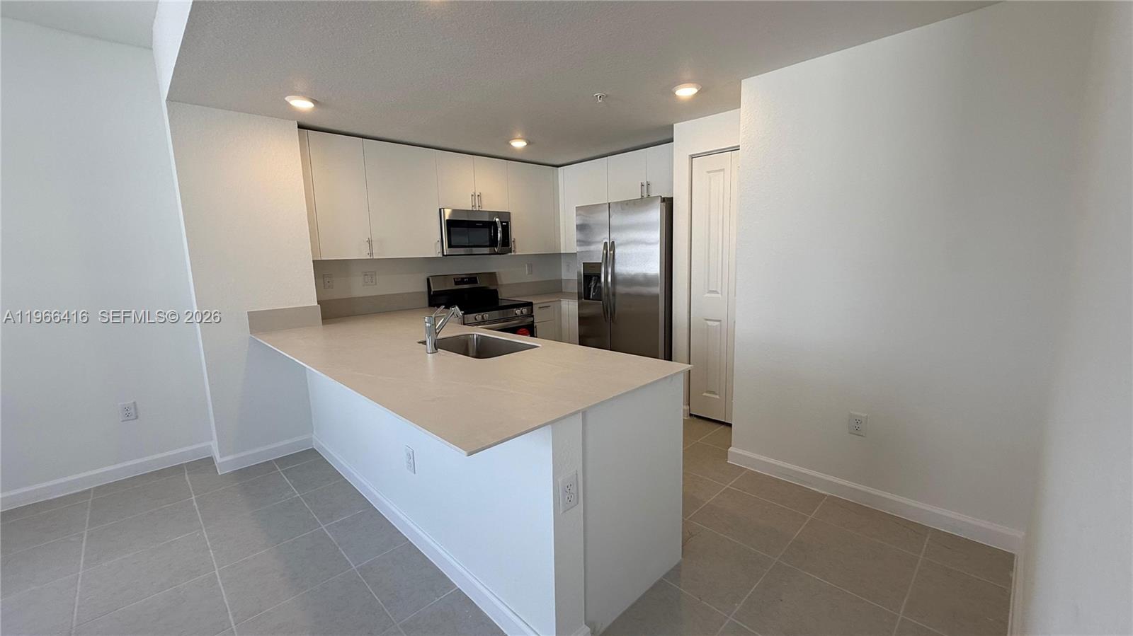 12420 Southwest 248th Street, Unit 10 Homestead, FL 33032 - Photo 5 of 16 a kitchen with kitchen island a sink appliances and cabinets